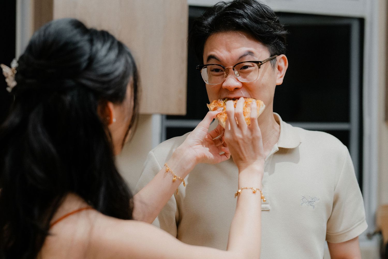 Couple shares homemade pastry while cooking together in kitchen.