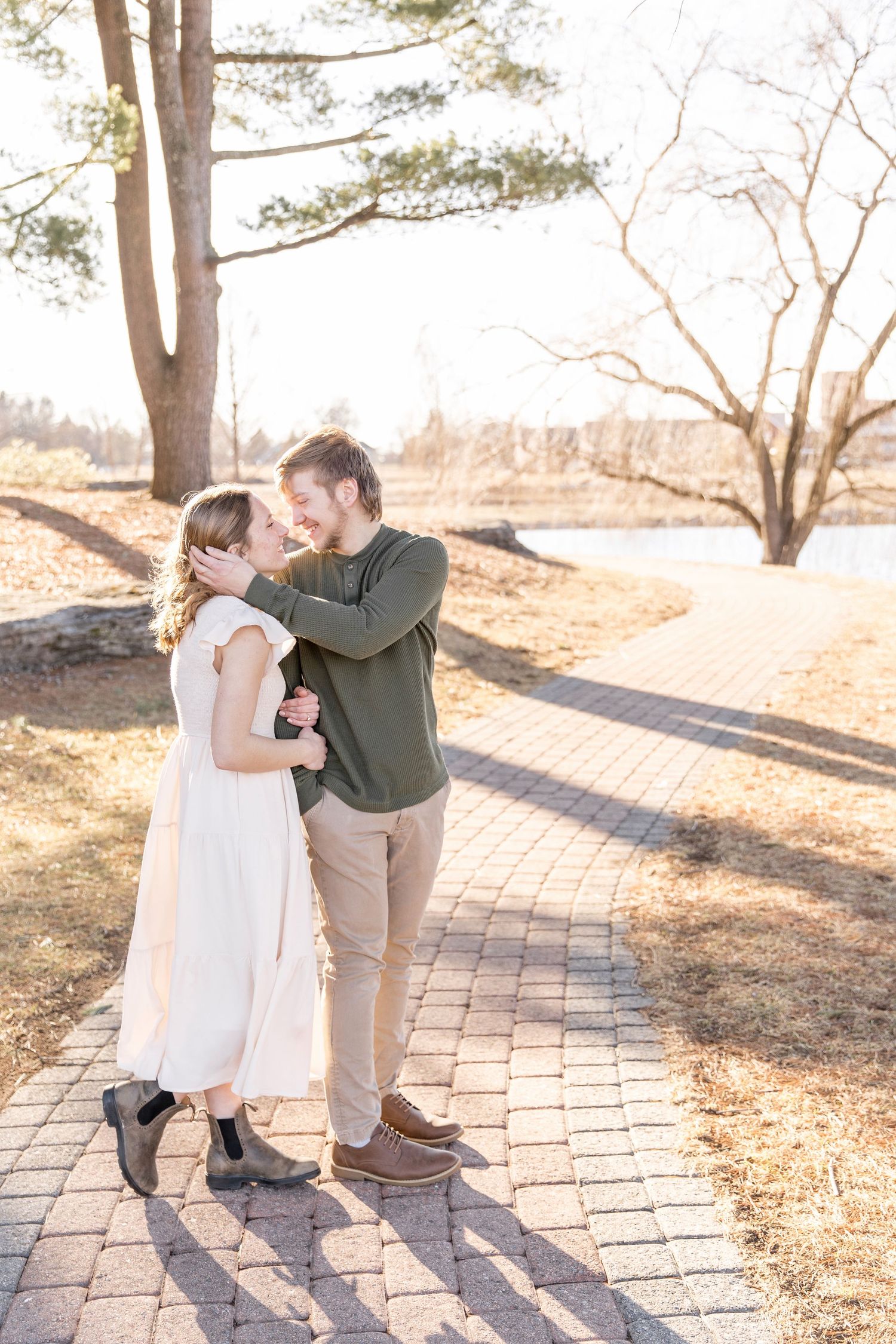 Tender outdoor family moment captured on stone path during golden hour with warm afternoon sunlight.