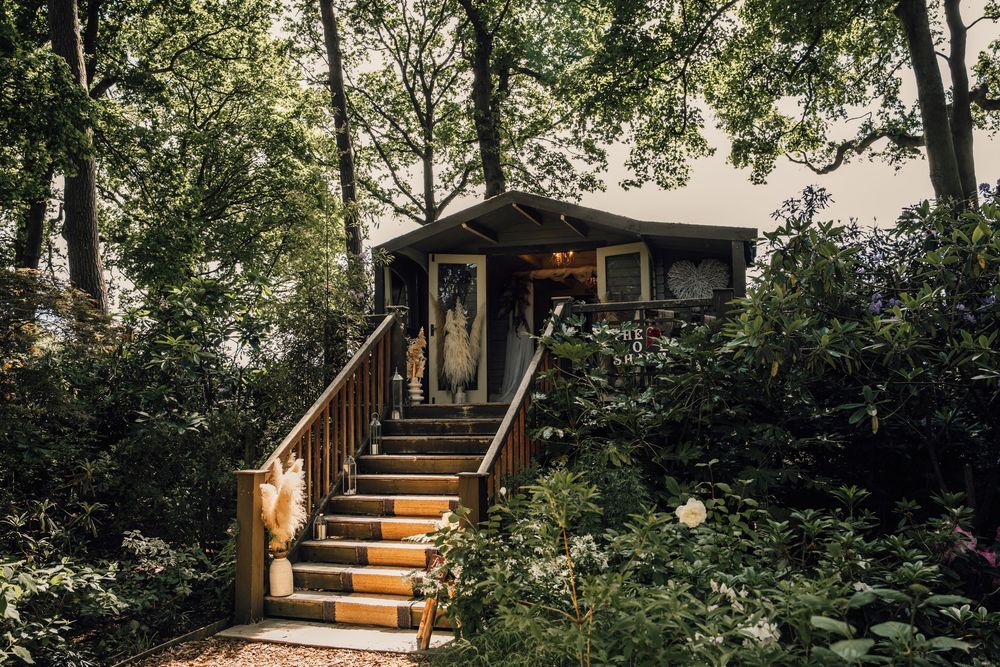 A wooden cabin with illuminated stairs nestled among trees and greenery at dusk.
