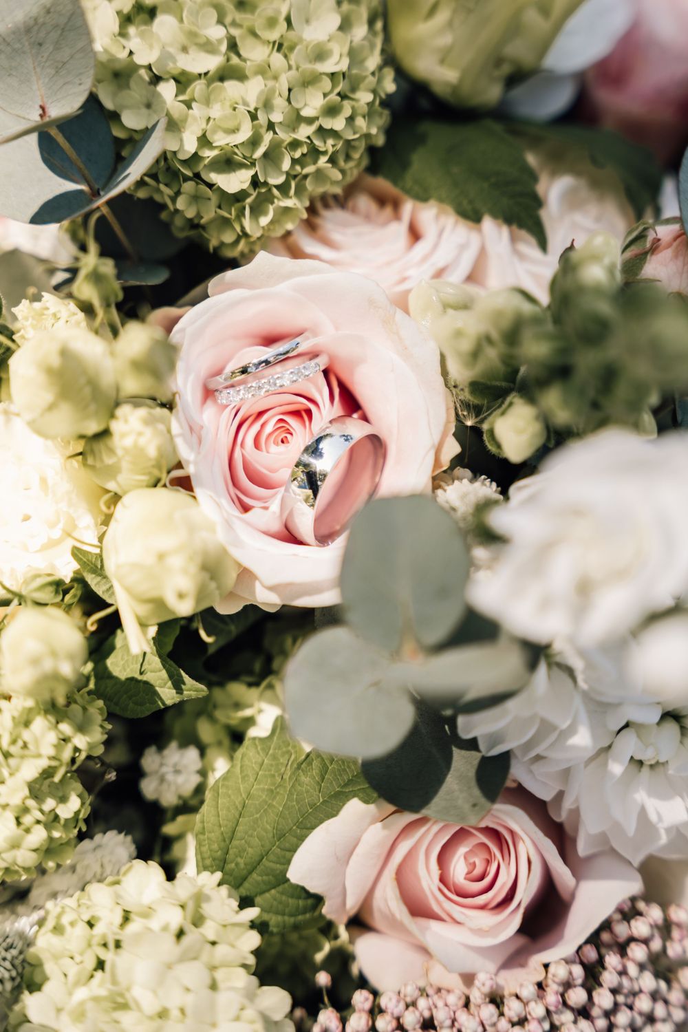 Delicate arrangement of pink roses and white hydrangeas with eucalyptus leaves.