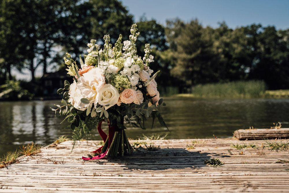 Wooden dock extending over water with floral arrangements in natural sunlight.