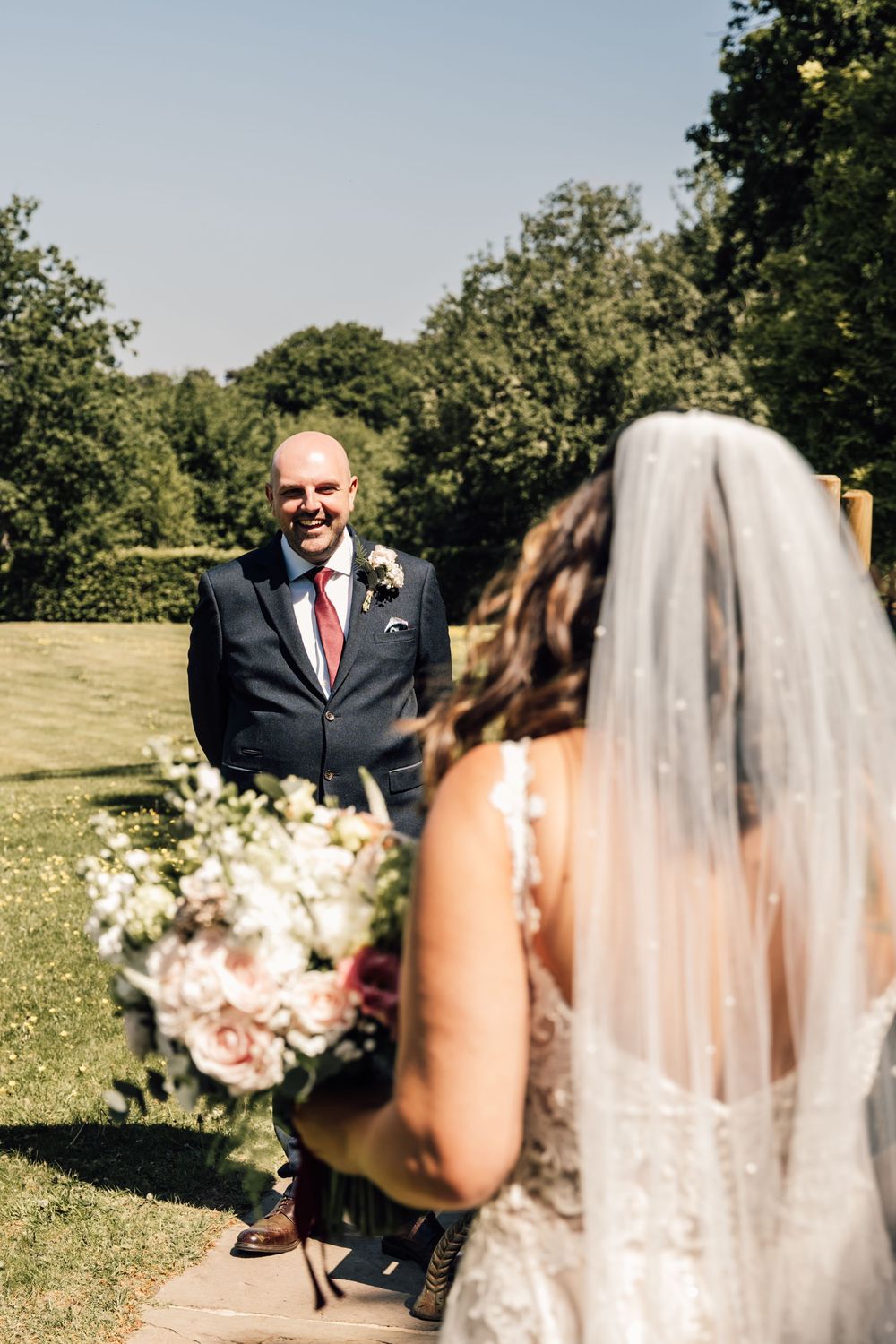 Wedding ceremony moment captured in bright sunlight with flowing white veil.