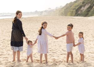 Family group walking together and holding hands along a scenic beach at sunset.