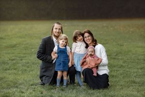Family group sitting together on grass in casual outdoor portrait.