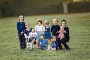Group of children posed together on grass with casual clothing.