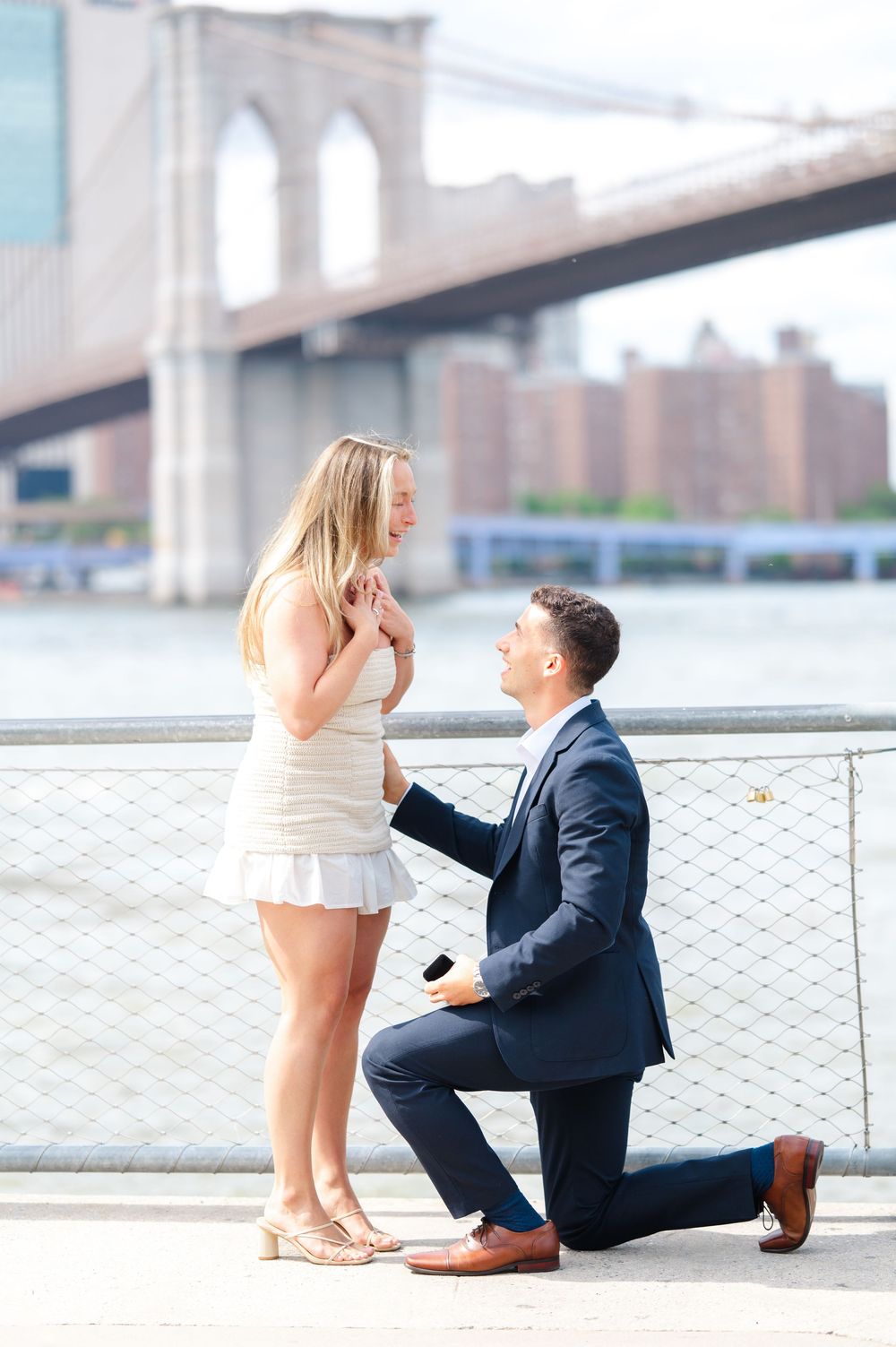 A romantic marriage proposal with the Brooklyn Bridge in the background as a couple shares a special moment by the DUMBO waterfront.