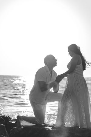 Silhouettes of two people sharing an intimate moment on a beach at sunset.
