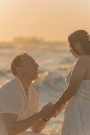 A couple sharing joyful moments on beach rocks during sunset.