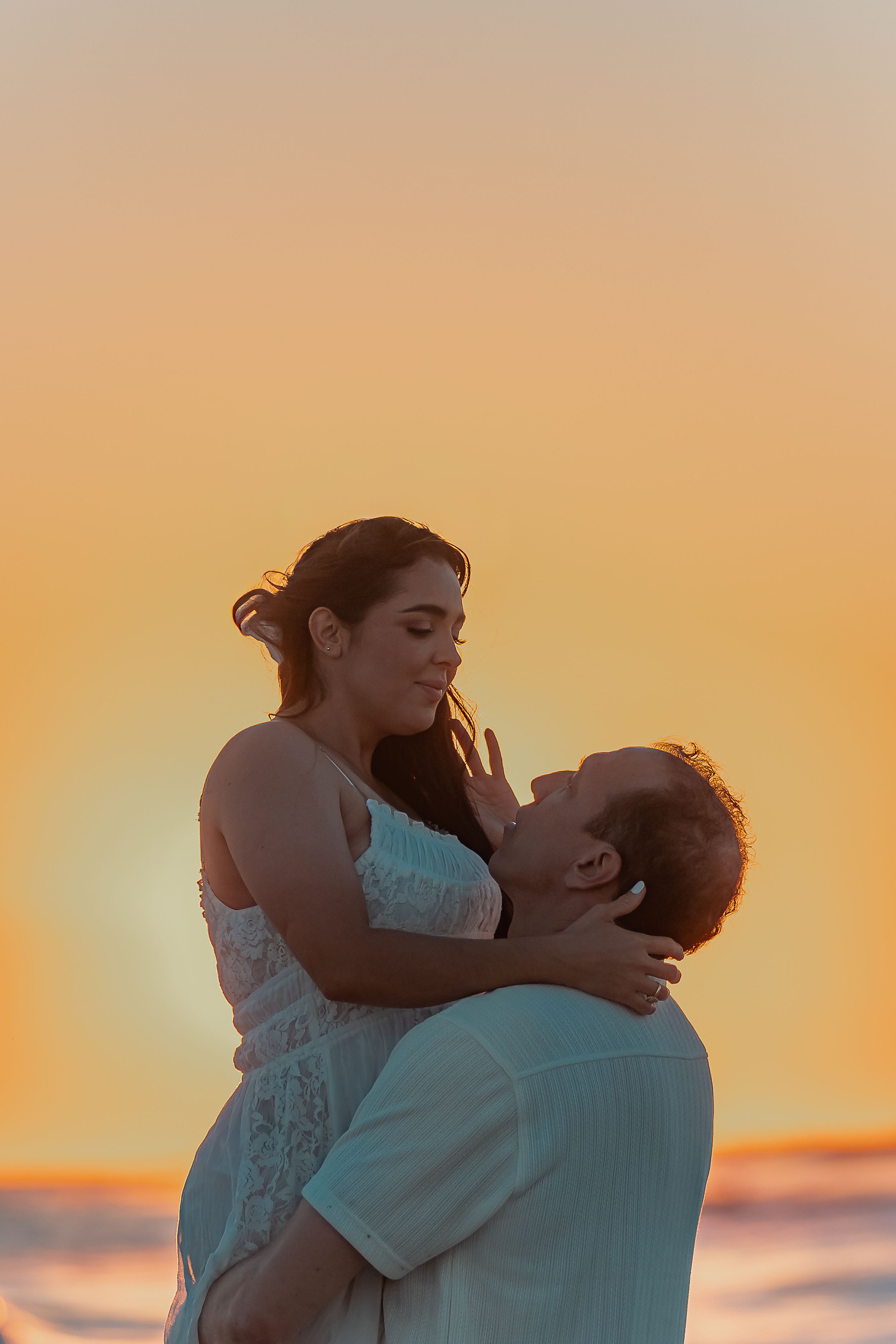 A couple sharing an intimate embrace on the beach during golden hour.