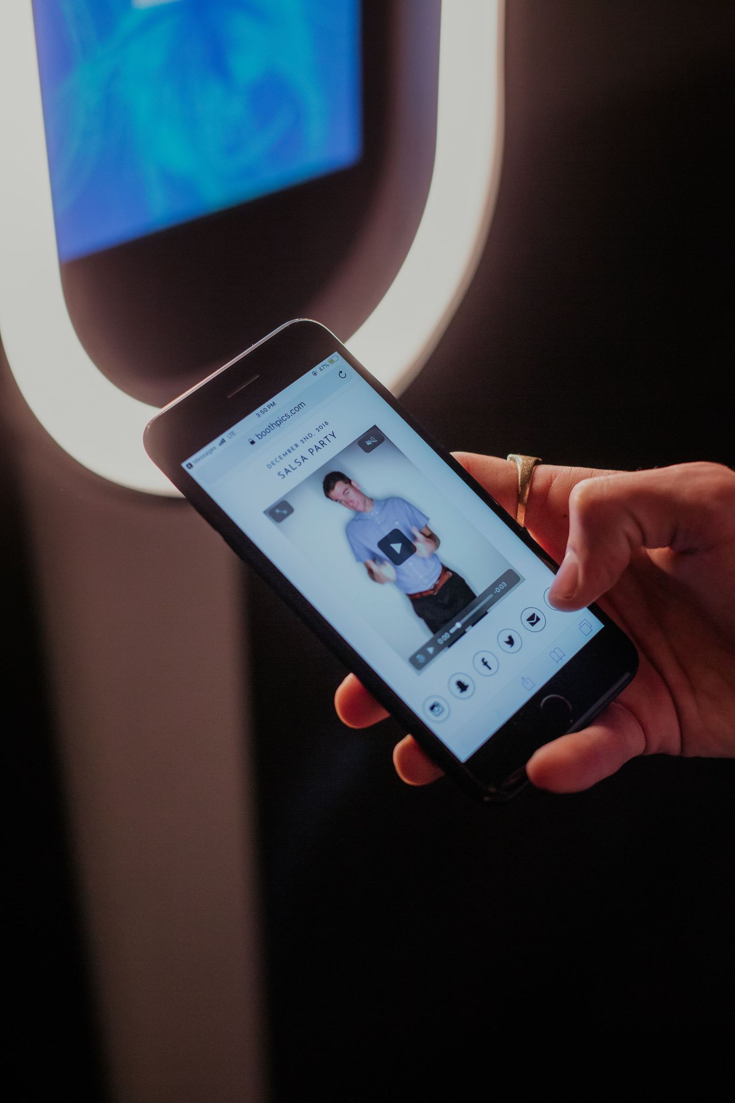 A hand holding a smartphone displaying a person's photo against the backdrop of an airplane window with blue sky.