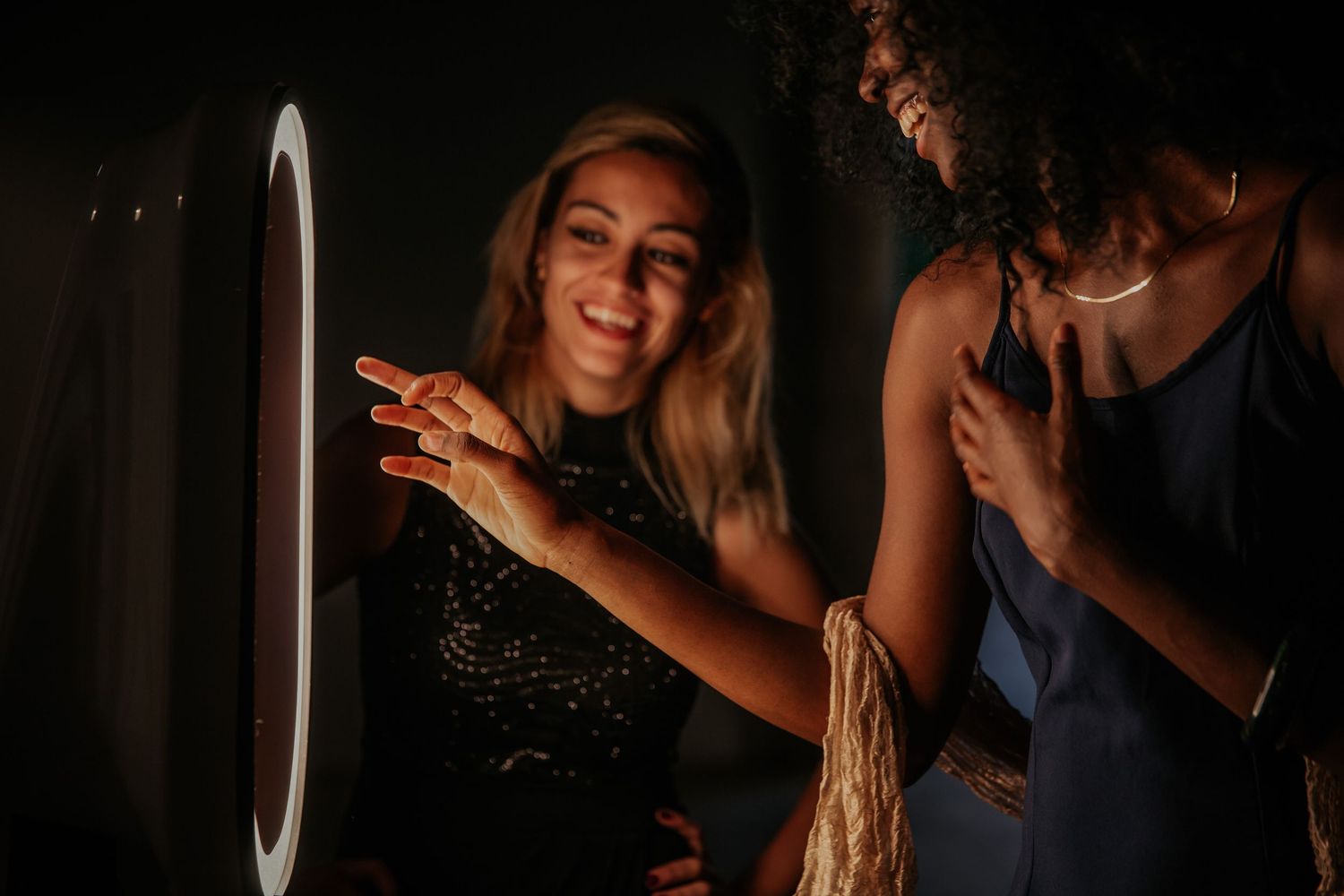 A dark and moody party scene with someone smiling and dancing in front of a white circular light at night.