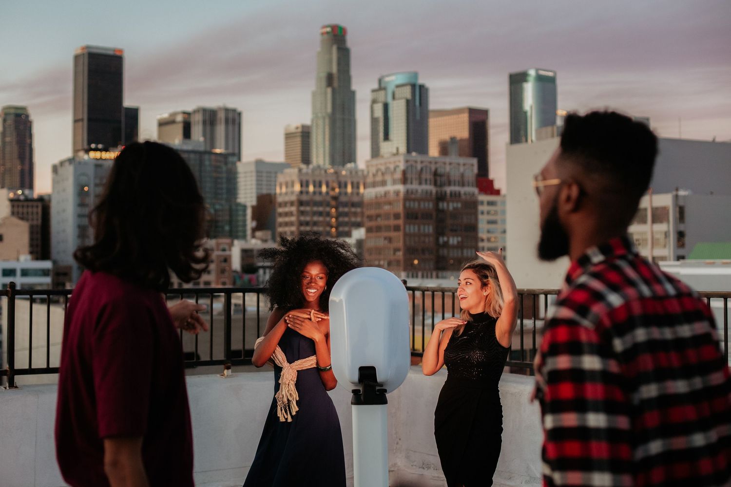 Group enjoying rooftop views of downtown LA skyline during golden hour.