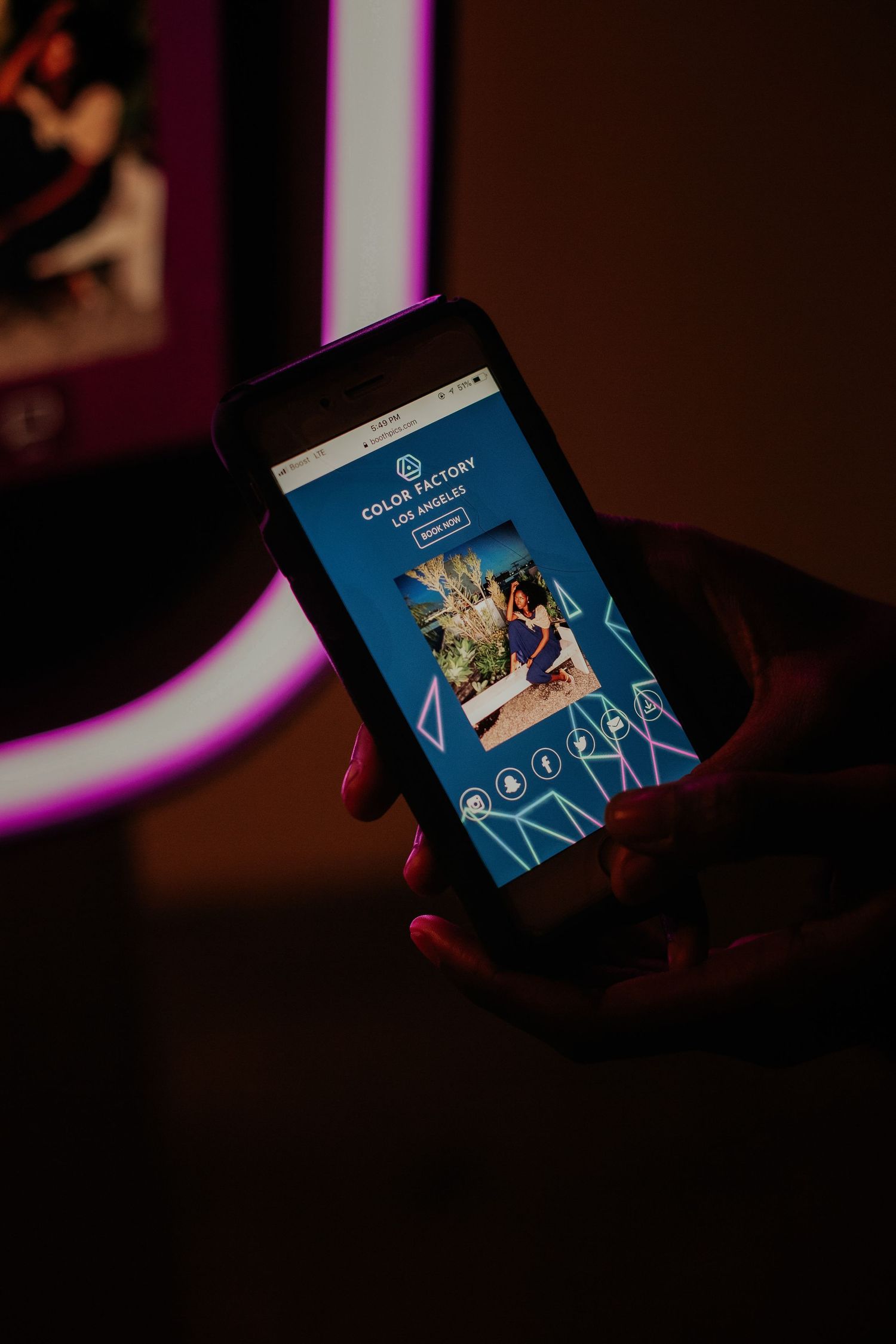 Hand holding smartphone displaying a dark app interface with blue glow in dimly lit environment.