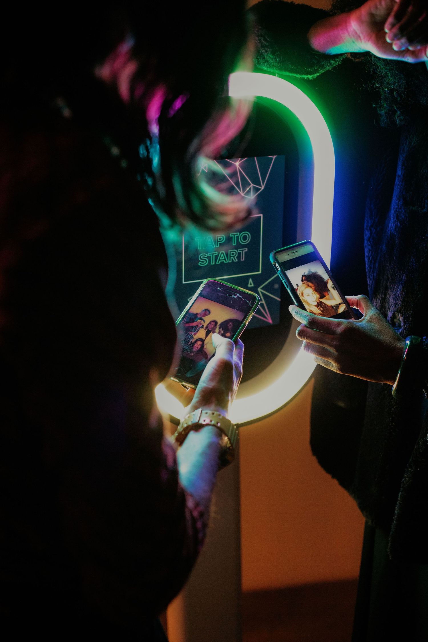 Several smartphones with glowing screens display social media content in a dark environment with colorful neon lighting.