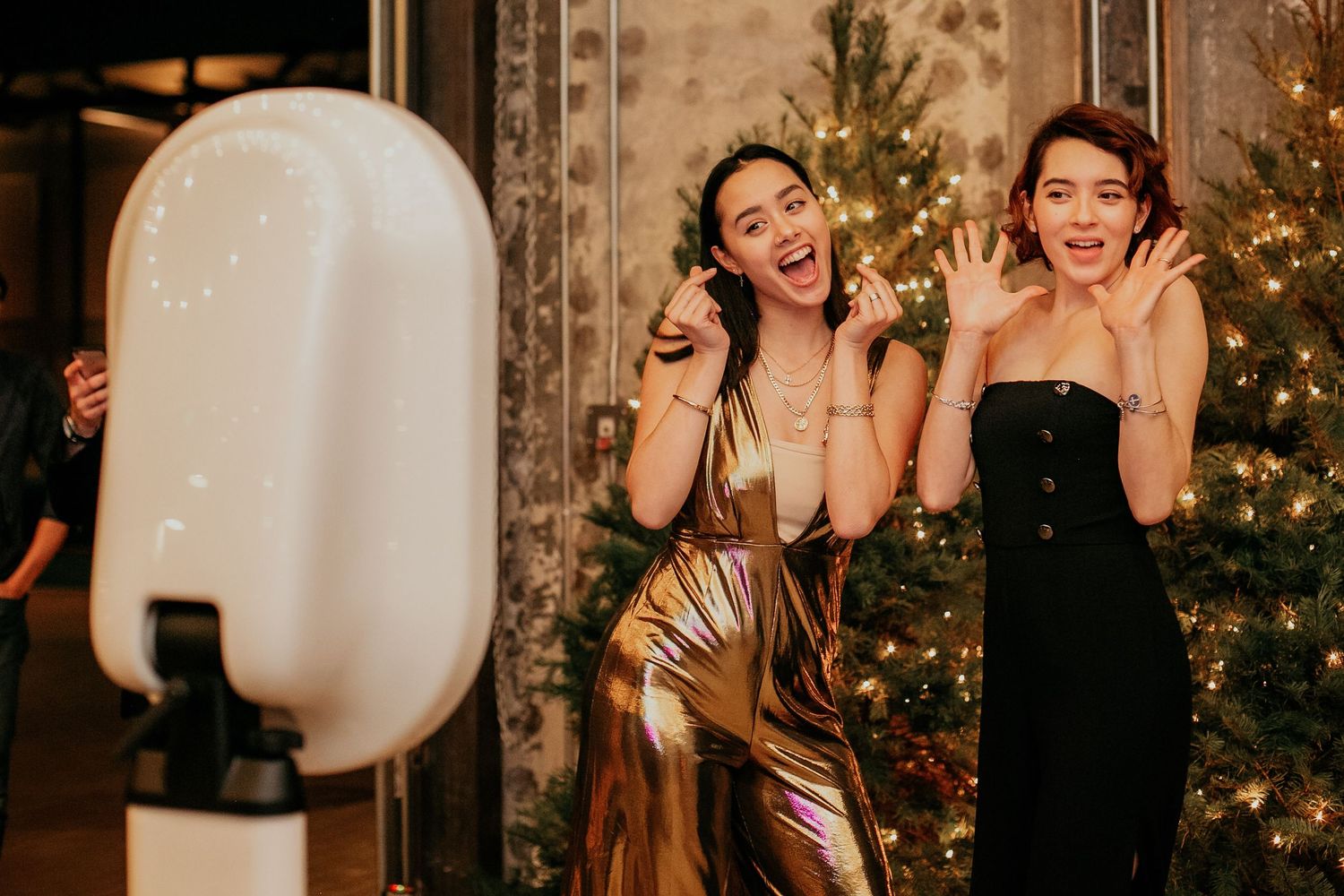 A festive party scene with decorative lighting and a Christmas tree in the background.