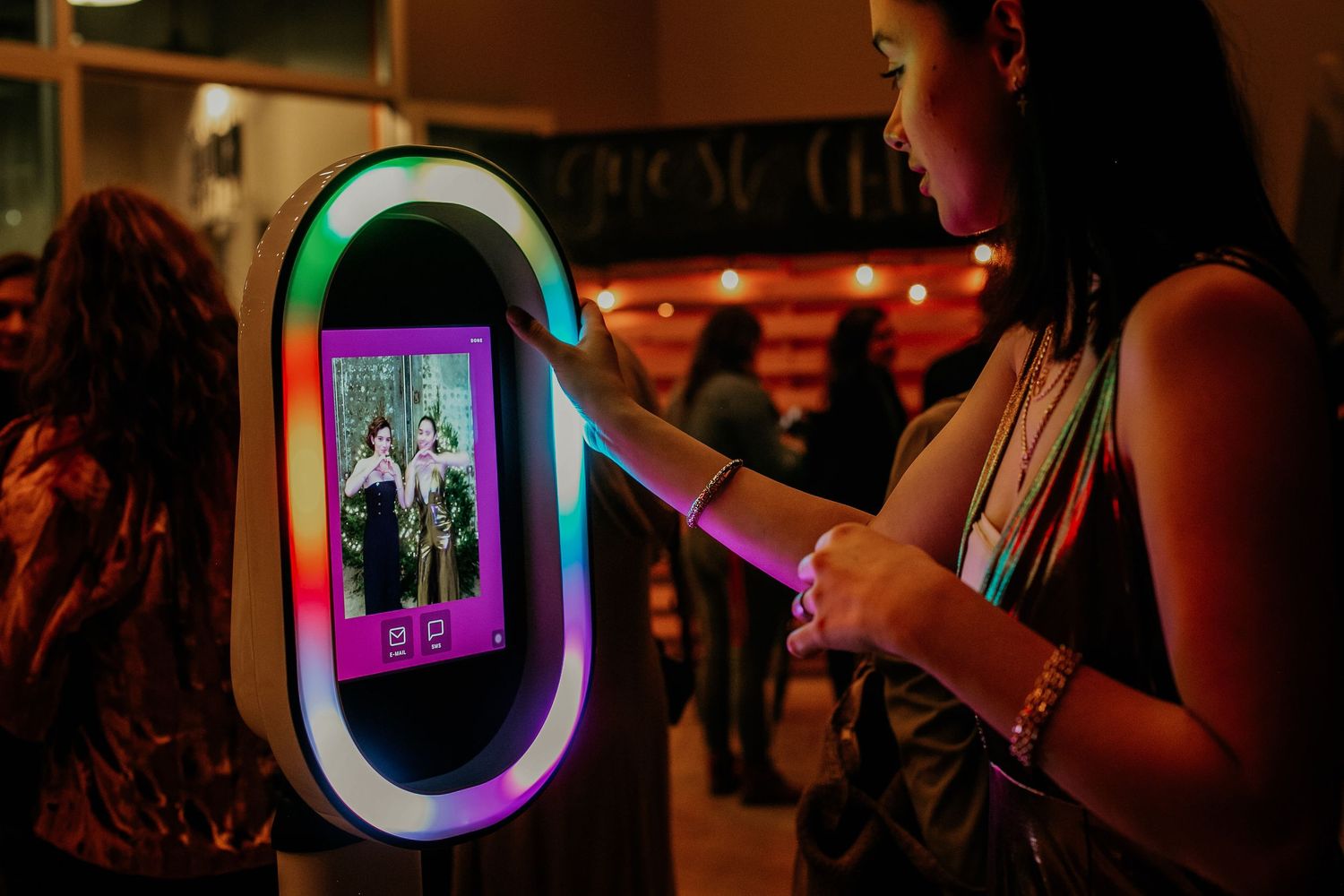 People use mobile phones in a dimly lit bar or club setting with ambient lighting creating a moody atmosphere.