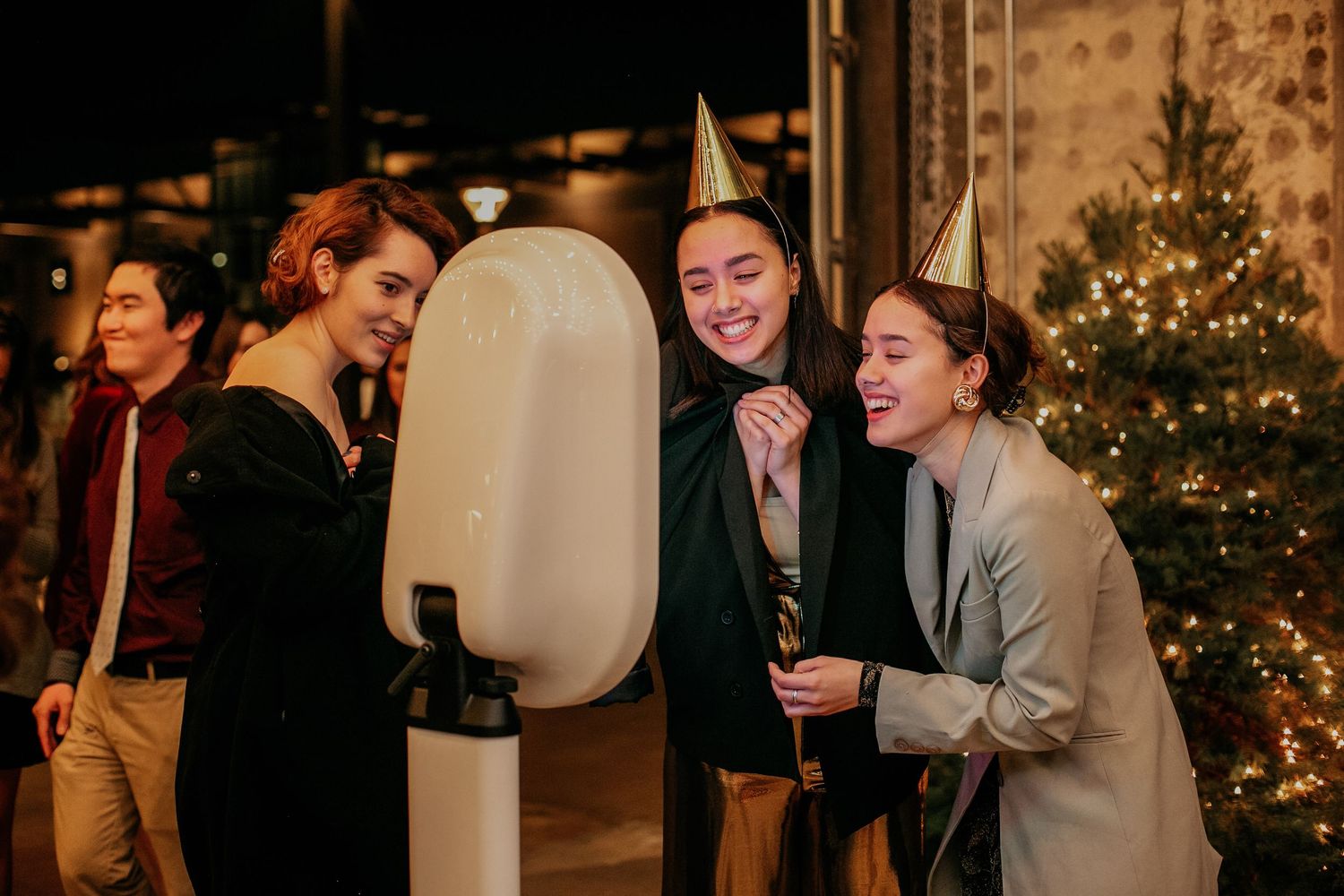 People enjoying and laughing around a modern photo booth with illuminated ring light at holiday party.