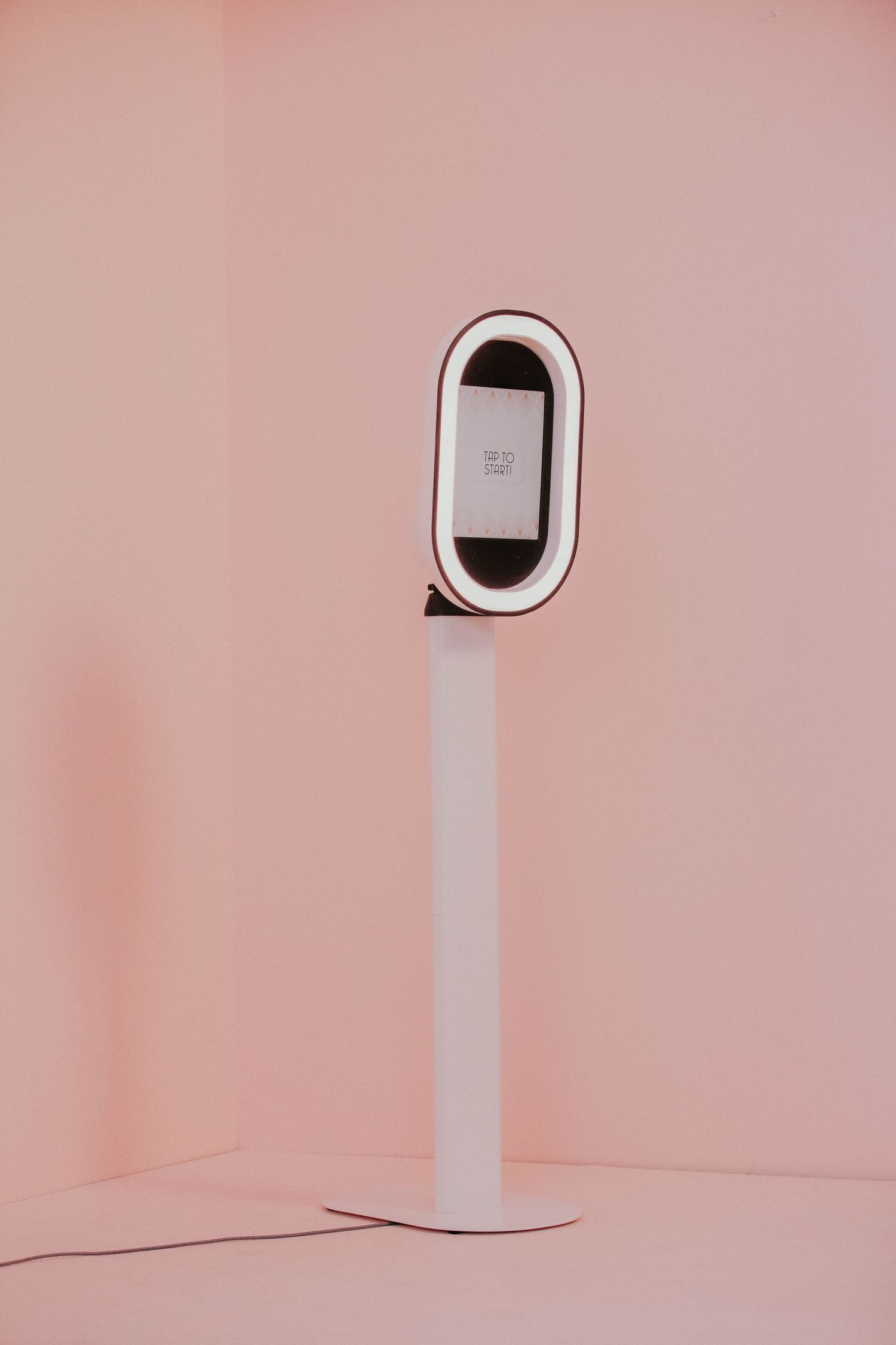 A minimalist white curved electronic device displayed against a pink background in sequence showing different angles.