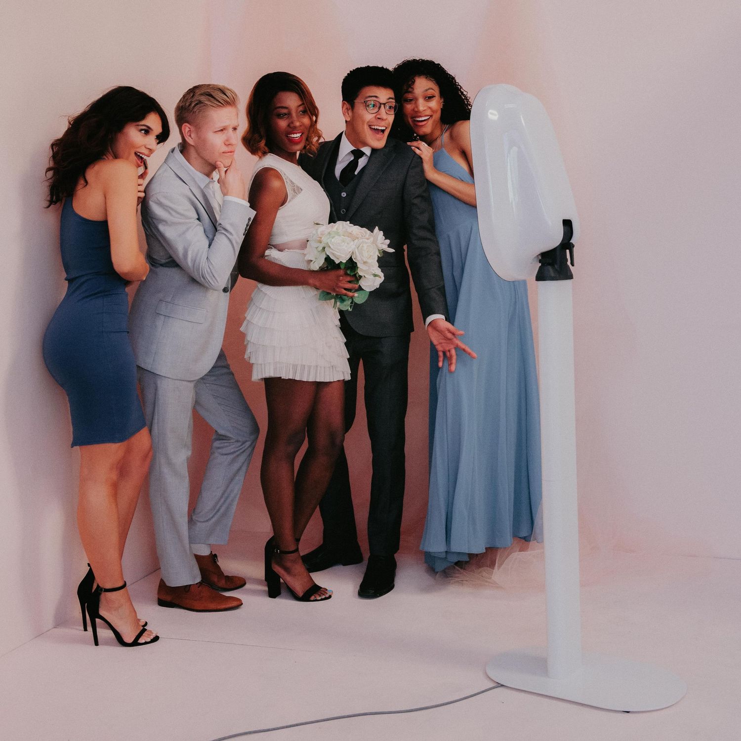 Group poses together in formal dresses and suits with a tripod-mounted camera for a professional photo shoot.