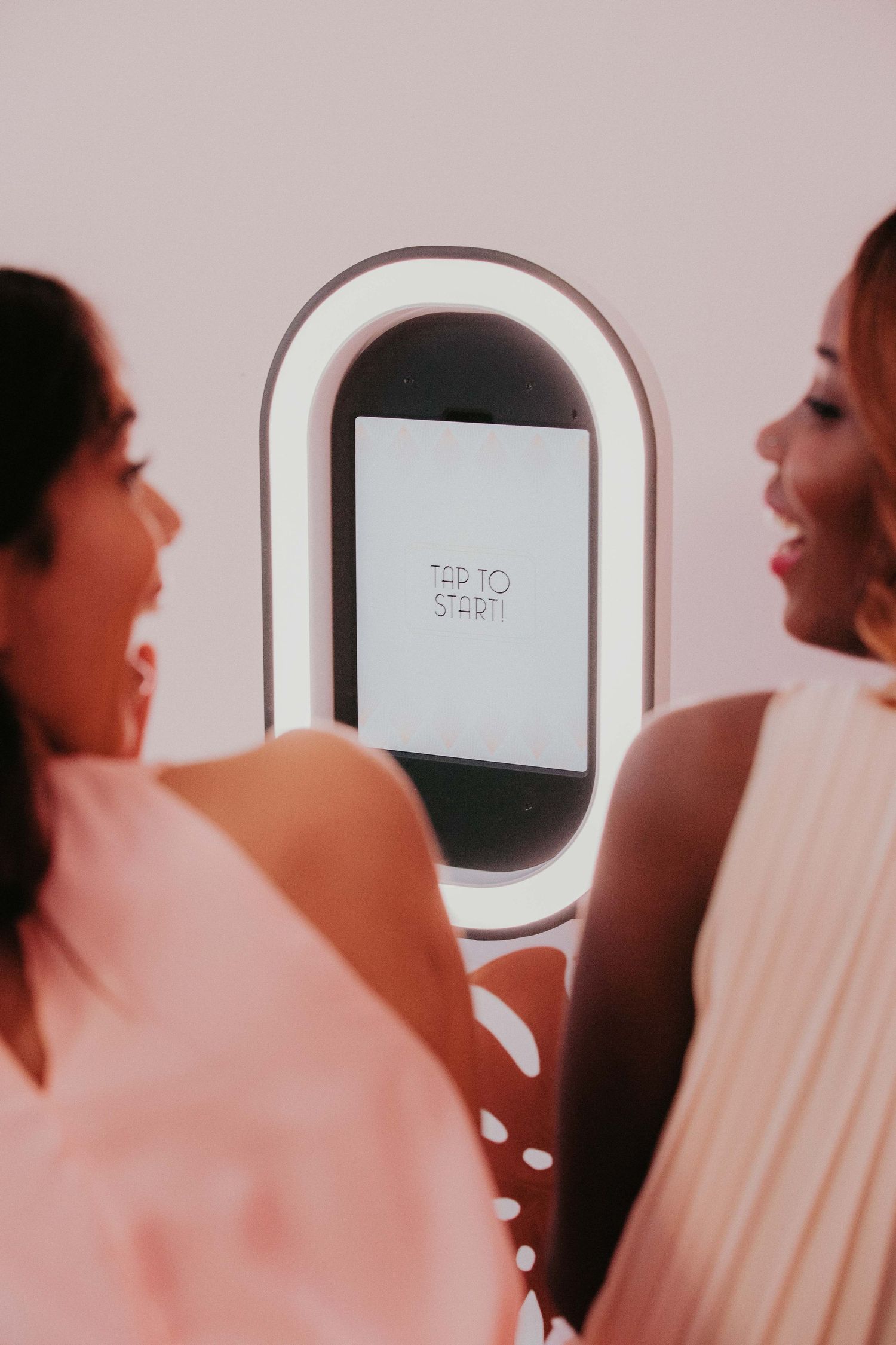 Two people look at a digital screen displaying 'Tap to Start' text in an aircraft cabin window setting.