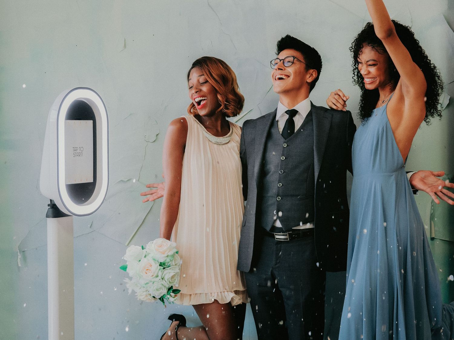 Wedding party members laugh and dance together in a lively celebration at a reception venue.