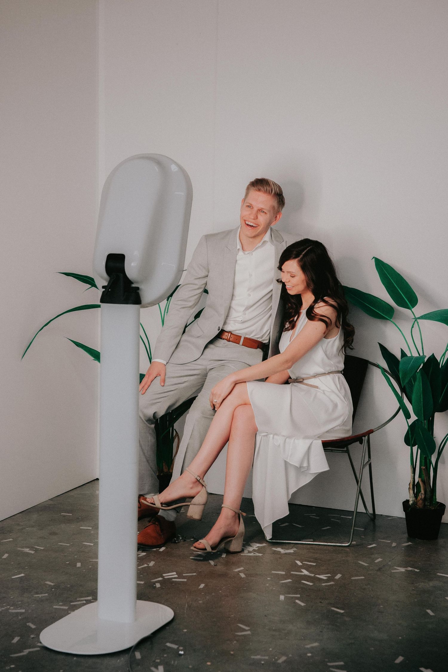 People in white attire sit on chairs against white wall with green plants, shown in multiple connected photos.