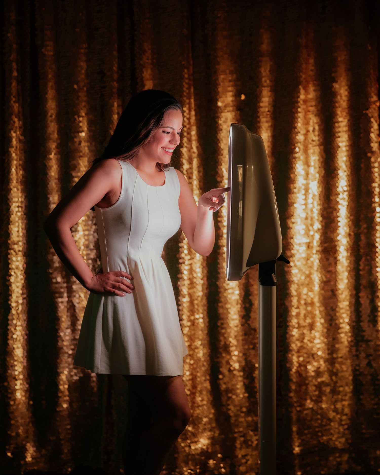 A performer in a white dress stands expressively against a golden curtain backdrop with dramatic lighting and a microphone.