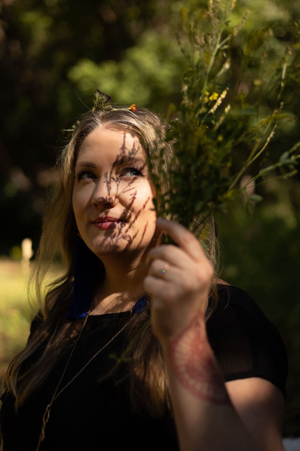 A portrait in dappled sunlight through leaves shows someone in a woman looking up with a dreamy expression.