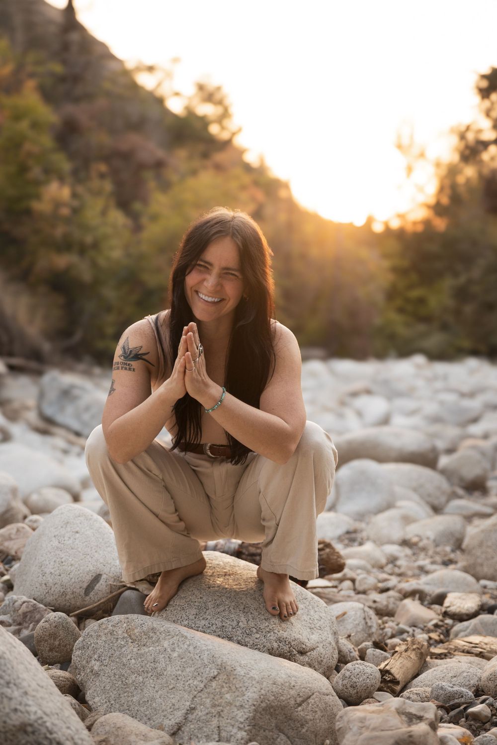 Person in casual clothing sits on rocky riverbed at sunset, creating a series of playful portrait poses.