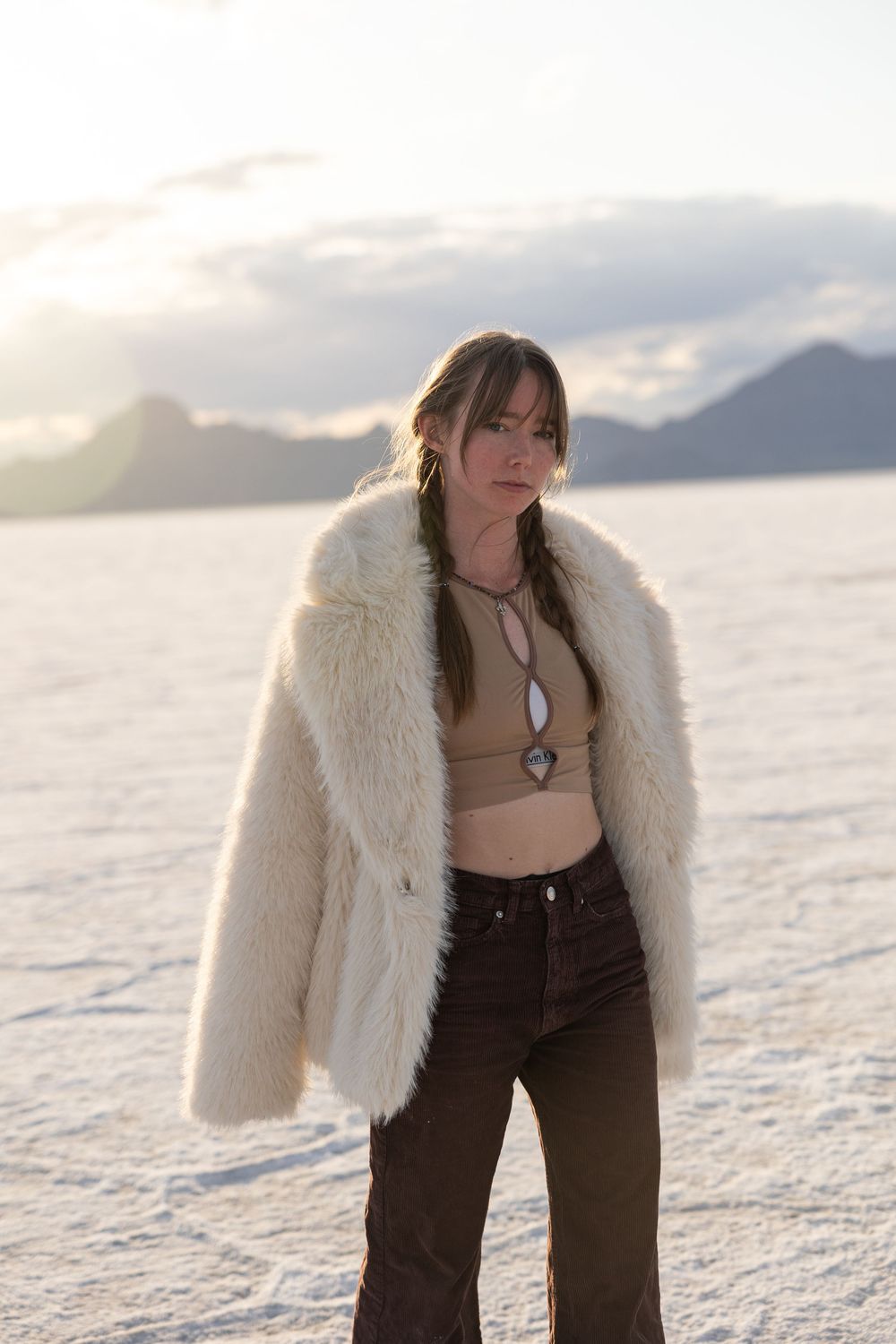 Model poses in a faux fur jacket for portait on salt flats.