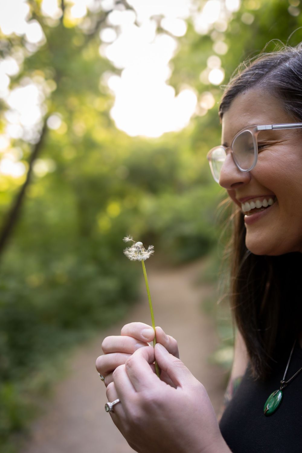 Woman smiles with a dandelion, making wishes.