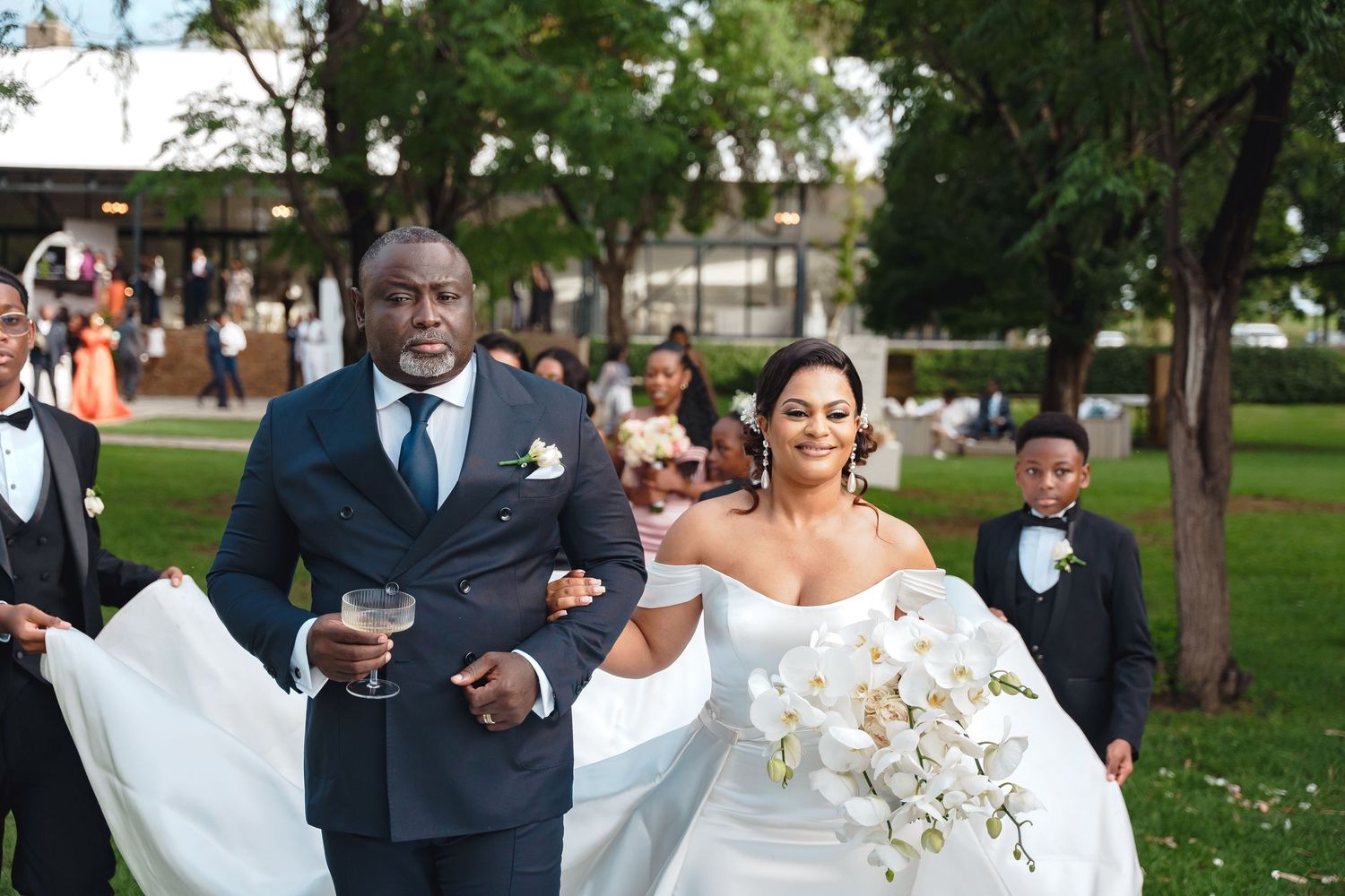 Couple in formal wedding attire share fun candid moments together while walking in a lush outdoor setting.