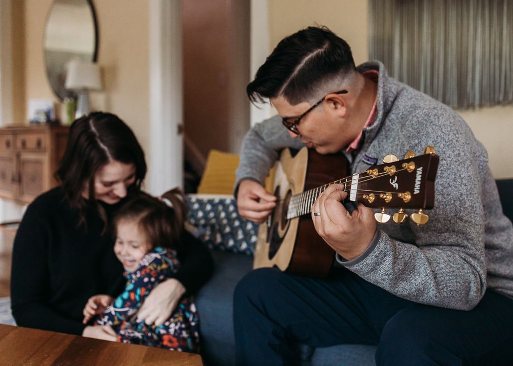 A family shares a cozy moment in their living room as acoustic guitar music fills the space during a relaxing afternoon.
