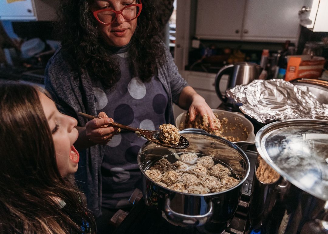 Two people share a joyful cooking moment in the kitchen while preparing food together in a warm domestic setting.