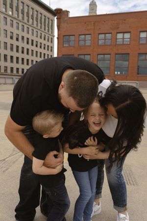 A family sharing laughter and embraces on a city rooftop.