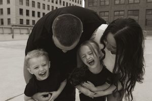 A group plays and laughs together on an urban rooftop with tall buildings in the background.