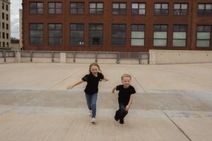 People walking and playing together on an urban rooftop with brick buildings in background.