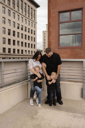 Candid family photography sequence showing joyful interactions against a city building.