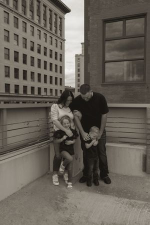 Black and white photo of a family sharing an intimate moment on a rooftop setting.