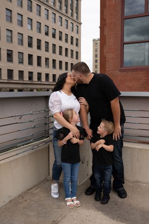 Sweet family moments captured in a series of casual outdoor portraits by a building.