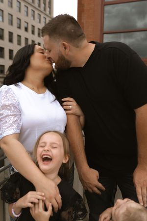 Joyful family photo sequence capturing genuine laughter and love against urban architecture.