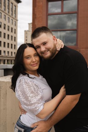Romantic couple portrait series against brick building backdrop in warm tones.