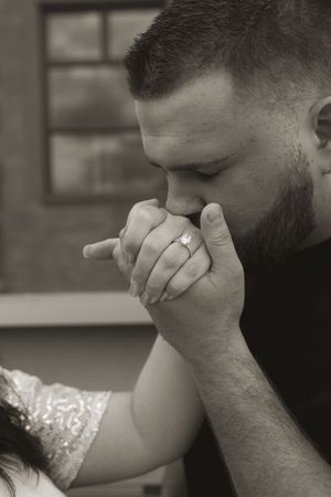 Close-up of a person covering their face with their hand while wearing a silver ring.