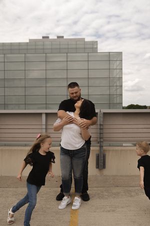 Playful couple dancing and dipping on an urban rooftop with cloudy sky backdrop.