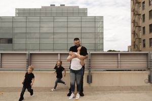 Wide shot of a couple celebrating on a rooftop with modern architecture in background.
