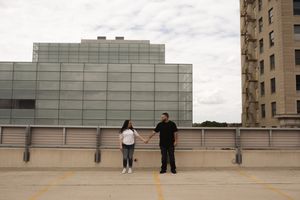 Long-distance shot of figures on a rooftop with urban buildings in the background.