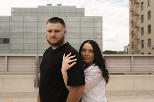 Couple in casual attire standing together on urban rooftop.