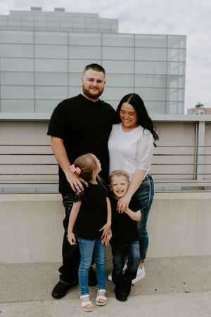 A family poses playfully together against a modern building exterior.