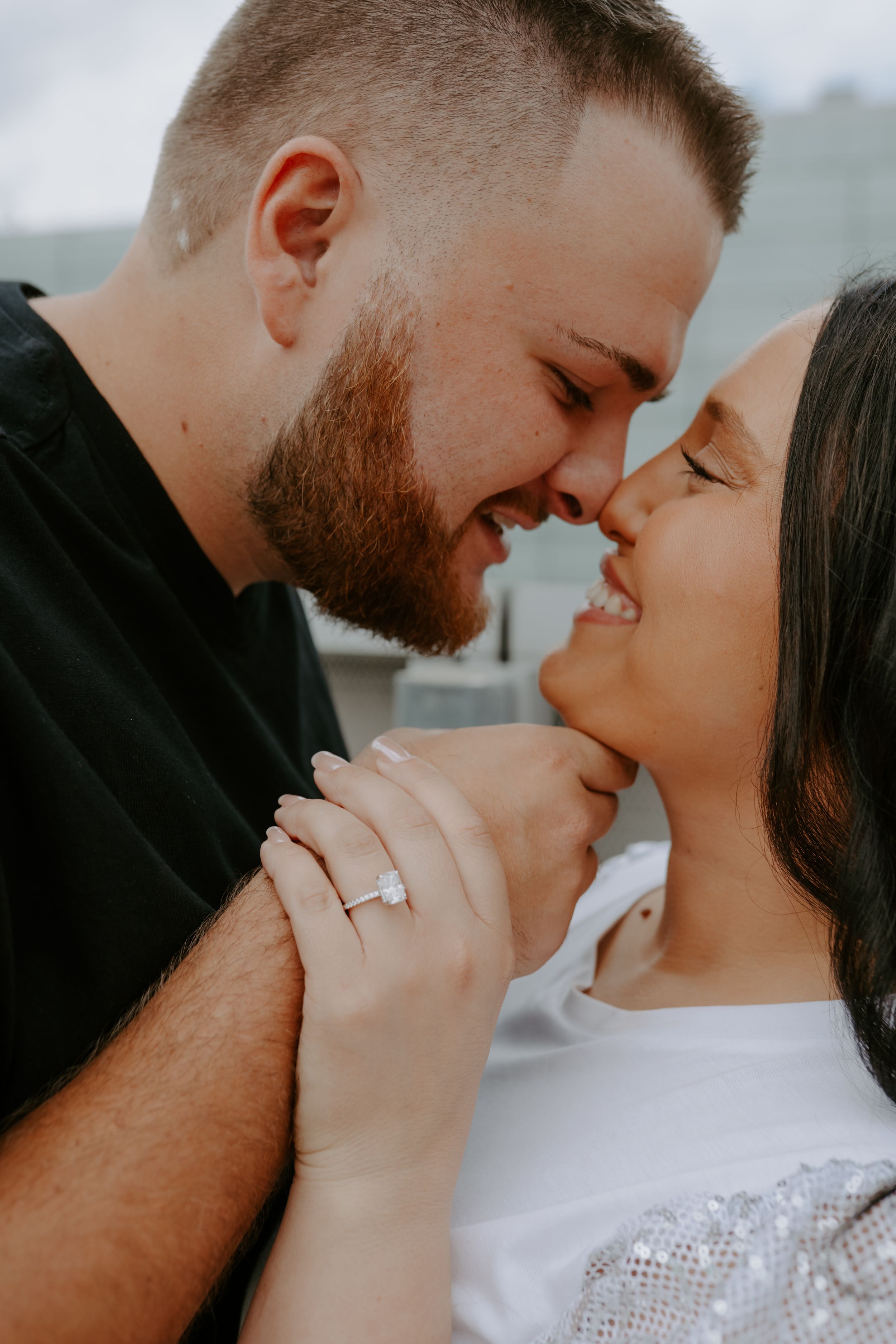 Close-up romantic portraits of a couple against an overcast sky background.