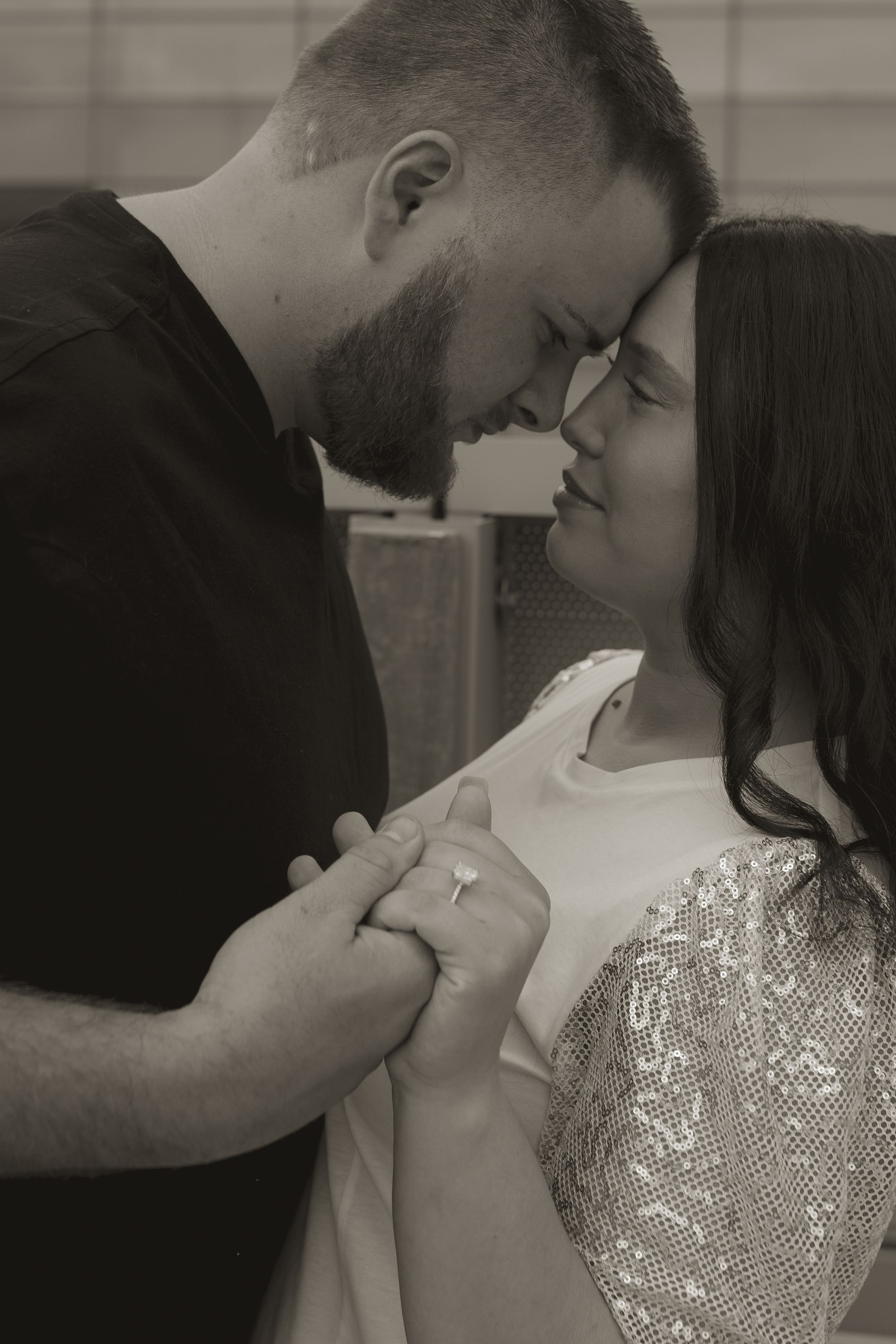 A romantic black and white photo showing an intimate moment between a couple with one wearing a sequined dress.